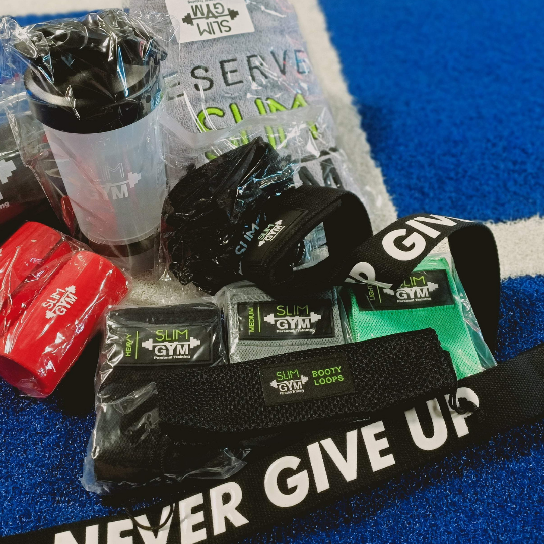 Complete Essentials Pack displayed on gym floor, including shaker bottle, booty bands, gym chalk, fat grips, lifting straps, gym towel, and palm protectors.