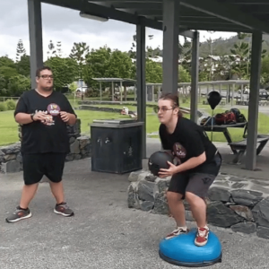 Catching a slam ball while maintaining balance on a Bosu ball and executing a squat.